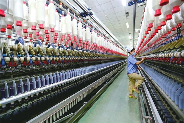 位于山东省青岛市即墨区龙山街道的一家纺织企业,工人在生产棉纱产品